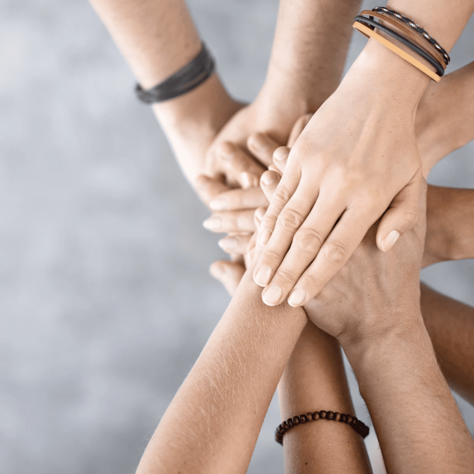 9 people putting their hands on top of one another in support.